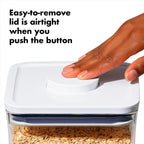 Hand pressing a button on a container with oats, text indicating an airtight lid feature.