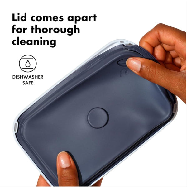 Person holding a dark blue container with a lid, showing that it comes apart for cleaning.