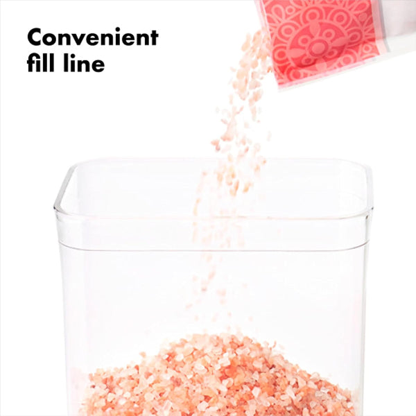 Pink Himalayan salt being poured into a clear container with text 'Convenient fill line'.