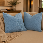 Light blue textured pillow on a beige couch in a living room setting.
