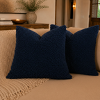 Navy blue textured pillow on a beige couch with a blurred indoor background